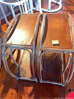Photo showing two vintage rattan side tables next to each other on a wooden floor, highlighting the damaged laminate tops and rattan frame construction.