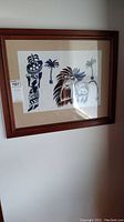 Full view of framed textile art hung on wall with wooden frame and tag attached