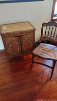 Wooden storage chest and cane seat chair together, showing overall wear and detailing.