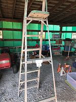 Full view of the lightweight 7-step metal step ladder with a top stool, showing the ladder set up upright on gravel inside a covered structure.