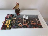 Resin bird figurine with unopened mailbox magnet wrap on a white surface.