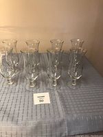 Eight clear crystal glasses arranged on a blue tablecloth, showing the set condition and quantity.