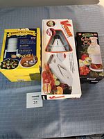Photo of three boxed kitchen cutting and chopping tools placed on fabric surface