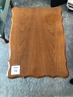 Top view of the wooden end table showing the smooth surface with scalloped edges and some wear.