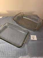 Two glass lasagna dishes on a table, one plain and one with floral pattern