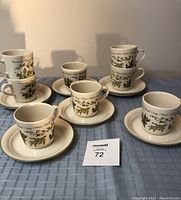 Full view of 8 cups stacked in pairs on 8 matching saucers, all displaying herb botanical designs and names.