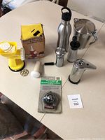 Photo showing all items on table including pasta maker, soap dispenser, two pepper grinders, water bottle, metal gravy boat, and compass in packaging
