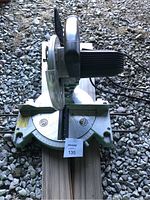 Top down view of the electric mitre saw showing the blade, base with angle gauges, and saw handle.