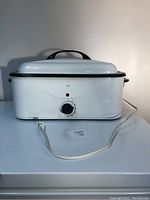 Front view of the white portable electric oven with attached power cord and temperature control knob.