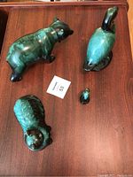 All four green glazed pottery animal figurines on wooden surface: bear, duck, cat, and squirrel visible with auction lot tag.