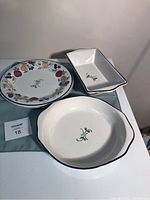 Set of four ceramic dishes showing the pie plate, loaf pan, and two plates with orchard medley fruit pattern.
