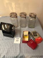 Overview photo showing three clear glass jars, Micorette Pocket Vue negative viewer with slides and box, and Pana-Vue slide viewer on a table.