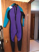 Full view of the women's wetsuit hanging on a door showing color pattern and shape.