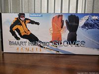 Box front showing branding and product use graphic for Fantaseal Smart Heated Gloves with winter sports imagery.