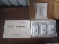 Box and contents showing three white in-wall smart switches inside packaging, labeled 'IN-WALL SMART SWITCH' on box top.