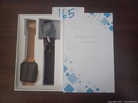 Photo of the metal smart watch fitness tracker with rose gold mesh strap and extra black strap in original packaging, lot number 165 visible.