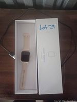 Photo of pink silicone smart watch in its box with charging cable visible.
