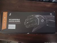 Box packaging labeled Rechargeable Heated Gloves with product image and features indicated.