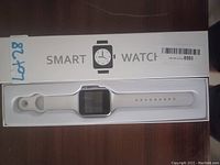 White silicone smart watch with box labelled SMART WATCH, showing watch inside with white strap and square face