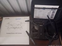 Photo showing the drone, remote controller, original box, and user manual inside a black carrying case.