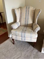 Front view of the wingback upholstered chair with visible fabric pattern and wooden legs