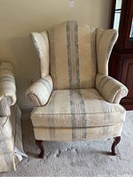 Front view of wingback upholstered chair showing striped and damask pattern fabric with cabriole wood legs