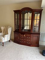 Front view of two-piece cherry wood china cabinet with upper glass display and lower storage with drawers and doors.