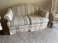 Front view of the Pennsylvania House upholstered love seat with striped and floral fabric upholstery on a carpeted floor.