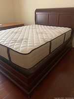Full view of queen sleigh bed with mattress and box spring showing wooden frame, mattress top and base.