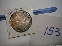 Photo of the obverse side of a 1962 Canadian silver dollar coin in a square holder showing the year 1959 and the wordings 'CANADA DOLLAR'