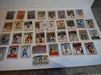 View of a spread of individual hockey player cards from the 1976-77 O-Pee-Chee set, laid out in rows on a flat surface.