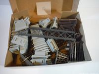 Overview of box with mixed grey and brown plastic train trestle pieces scattered inside showing various structural elements.