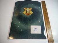 Folded cover of the display book with gold Hogwarts H crest on starry dark background