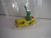 Yellow vintage die-cast convertible toy car with Kermit The Frog figure inside, shown in a clear plastic bag.