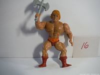 Front view of He-Man action figure holding axe, showing face, chest, and boots.