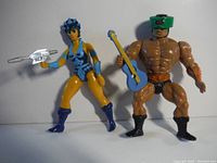 Female figure in blue and yellow with silver gun and male figure with green visor and blue guitar shown side by side.