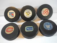 Top six pucks showing team logos: Rangers, Penguins, Flames top row; Canadiens, Canucks, Maple Leafs bottom row