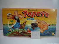 Top view of Popeye board game box with colorful illustrated lid featuring Popeye characters on an island, title prominently displayed.