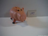 Front angled view of the pink pig figure, showing facial details and standing pose with tag number 137.