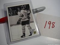 Front view of the Tim Horton hockey card in protective sleeve with a red and white pen next to it.