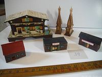 Set of 5 wooden buildings shown on white background with measuring tape in front for scale