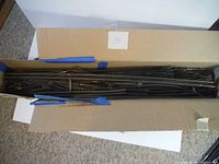 Top-down view of large box containing multiple lengths of HO scale train track sections, taped to secure them together.