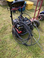 Overall view of power washer unit, hose and spray gun mounted on frame