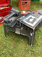 Craftsman brad nailer with box on a black plastic step stool/toolbox on grass.