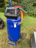 Front view of Campbell Hausfeld blue vertical air compressor on wheeled base