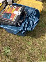 Photo of blue tub filled with folded blue tarp and paint tray resting on top.