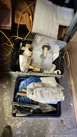 Plastic bins containing drywall and painting tools including trowels, rollers, and scrapers