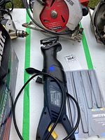 Photo showing both the Black & Decker circular saw with red blade and the Mastercraft reciprocating saw with its power cord and included blades pack visible on table.