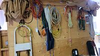 Overview of ropes, straps, cords, and apron hanging on wooden wall