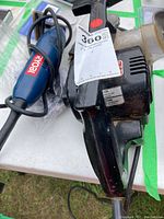 Top view showing the side and label of the Ryobi blue sander with power cord, alongside the Craftsman planer black handle and part of the front blade plate showing.